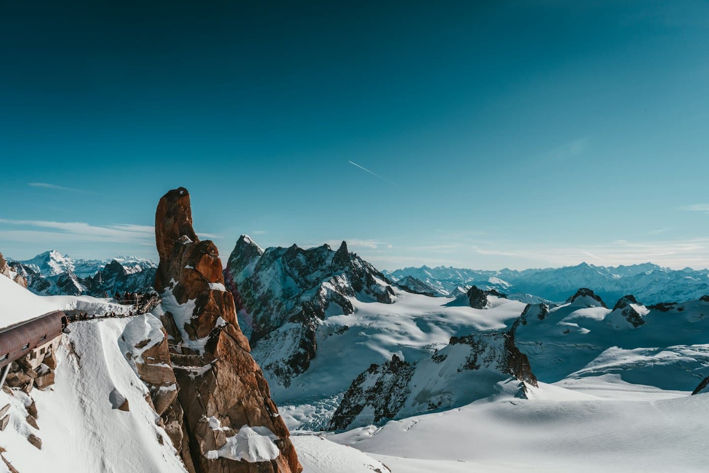 Rugged brown rock formation rising from a snowy mountain landscape.