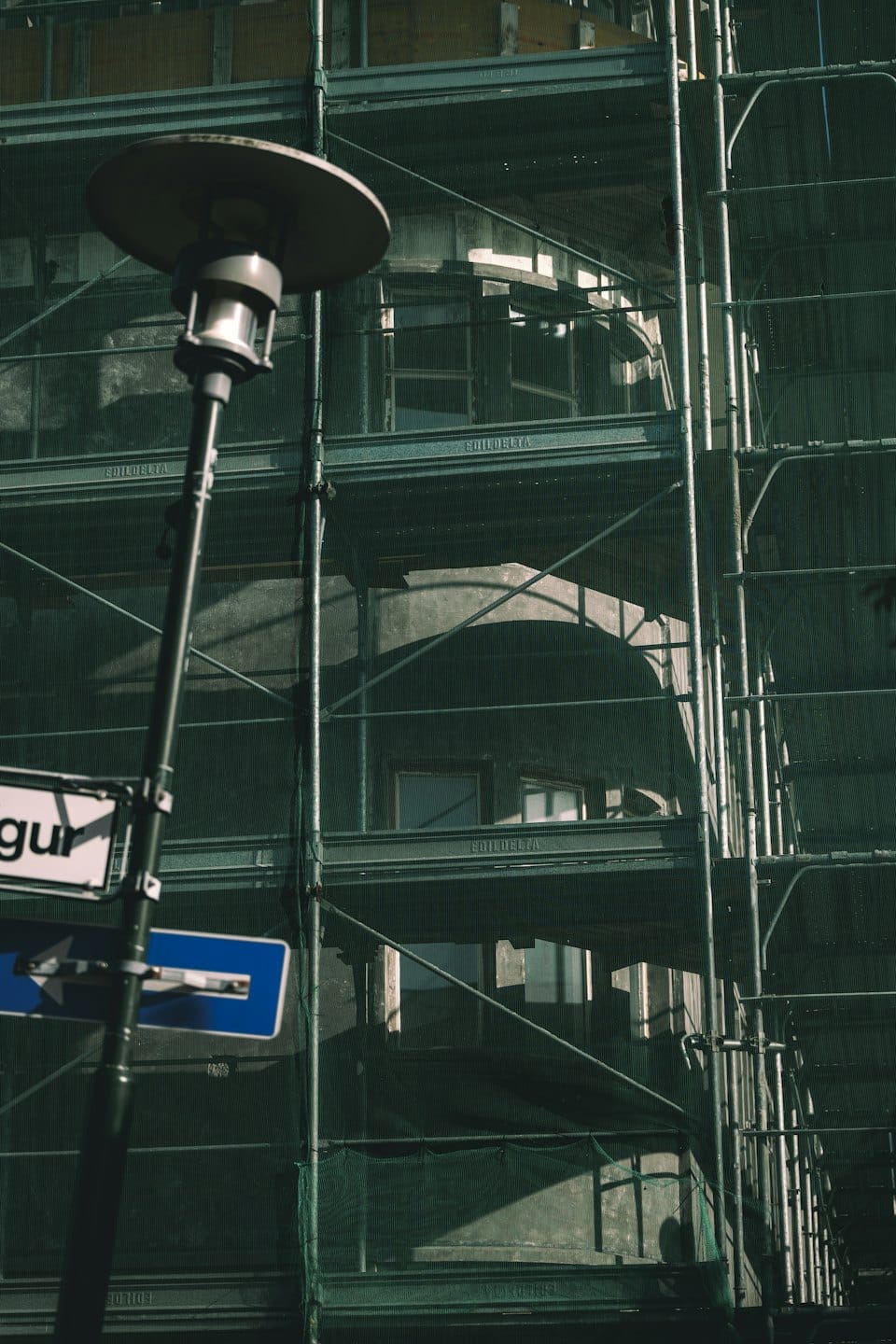 Metal scaffolding and green netting surround a building under renovation.