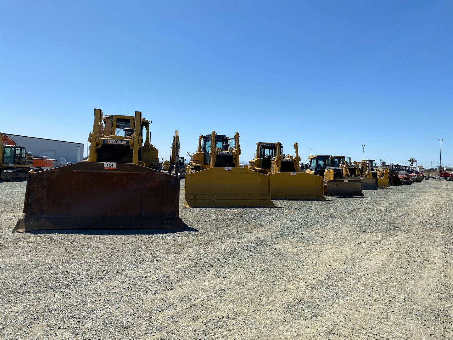Yellow bulldozers and heavy construction equipment parked in a gravel lot.