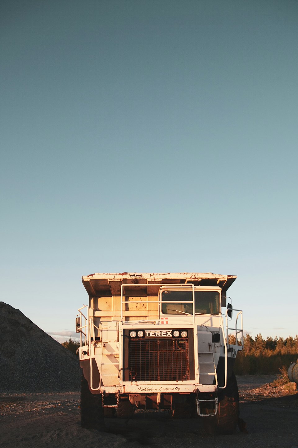 A white mining truck parked near a pile of gravel.