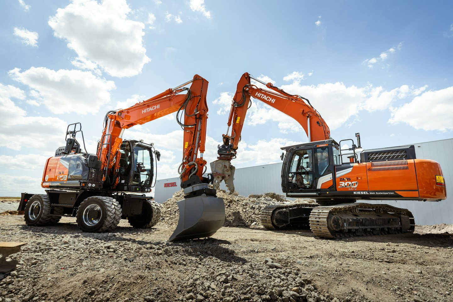 Two orange Hitachi excavators parked side-by-side on a construction site.
