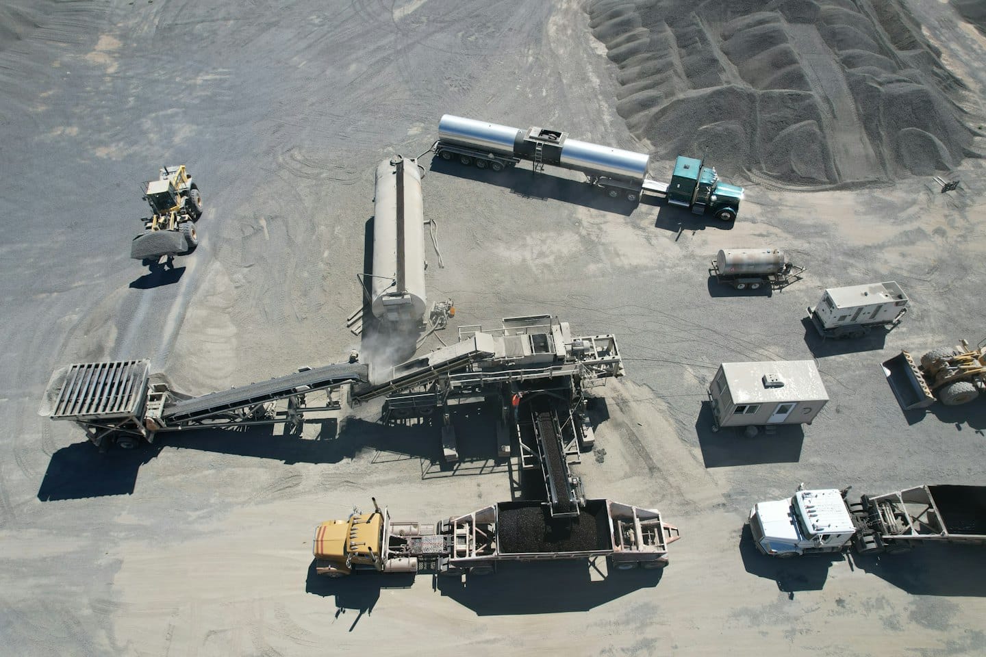 Heavy machinery and conveyor belts process gravel at a quarry.